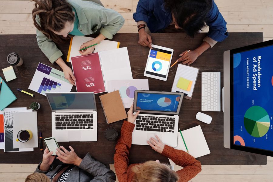 Overhead view of a team reviewing performance charts and an ad-spend breakdown around a desk